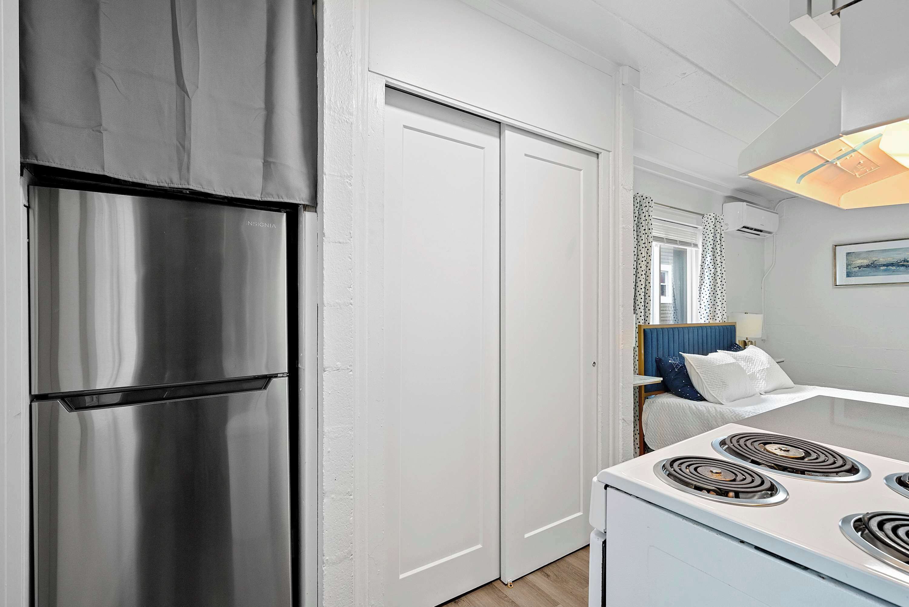 A kitchen with a stainless steel refrigerator, white cabinets, and a white stove.