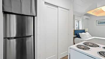 A kitchen with a stainless steel refrigerator, white cabinets, and a white stove.