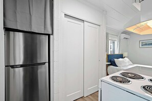A kitchen with a stainless steel refrigerator, white cabinets, and a white stove. - Chic City Retreat 93G (Columbus)