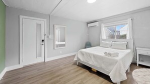 A bedroom with a bed, bedside table, and a window. - Chic City Retreat 93D (Columbus)