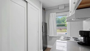 A kitchen with a built-in stove, a refrigerator, and a window with curtains. - Chic City Retreat 93D (Columbus)