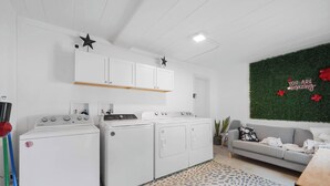 A laundry area with two washing machines, a drying machine, and a cabinet above. - Chic City Retreat 93D (Columbus)