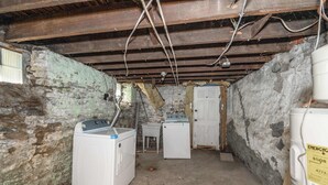 Ein Waschraum mit zwei Waschmaschinen, einem Trockner und einem Warmwasserbereiter.