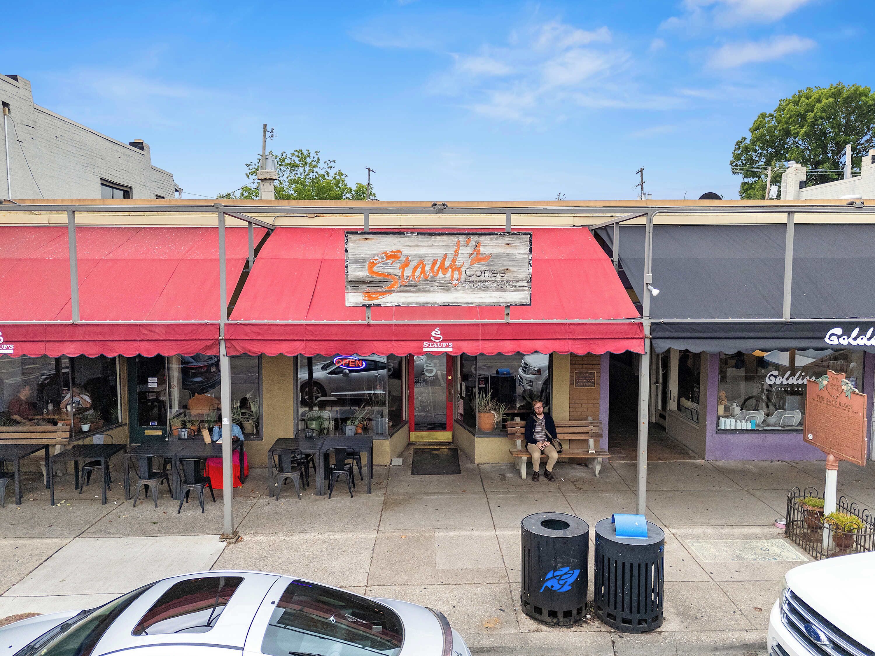 A storefront with a red awning, outdoor seating, and a sign that reads "Stash's".