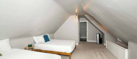 Een slaapkamer met twee bedden, een plafondlamp en een radiator.