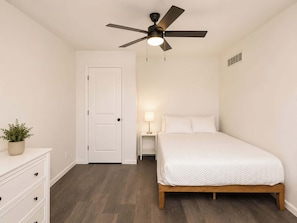 A bedroom with a bed, a nightstand, a ceiling fan, a door, and a dresser. - Near Kings Island, 5BR Family Retreat, Sleeps 10 (Mason)