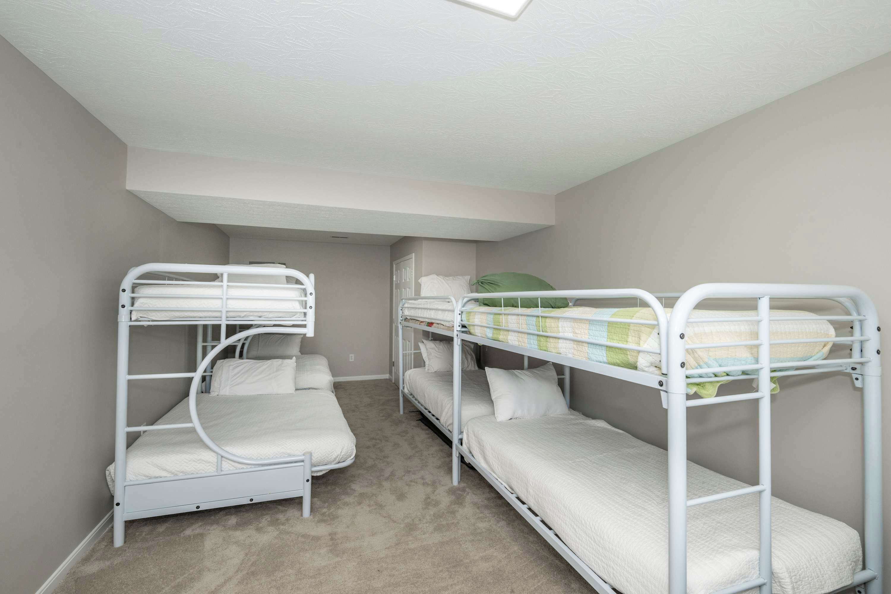 Een kamer met stapelbedden, vloerbedekking en een dakraam.