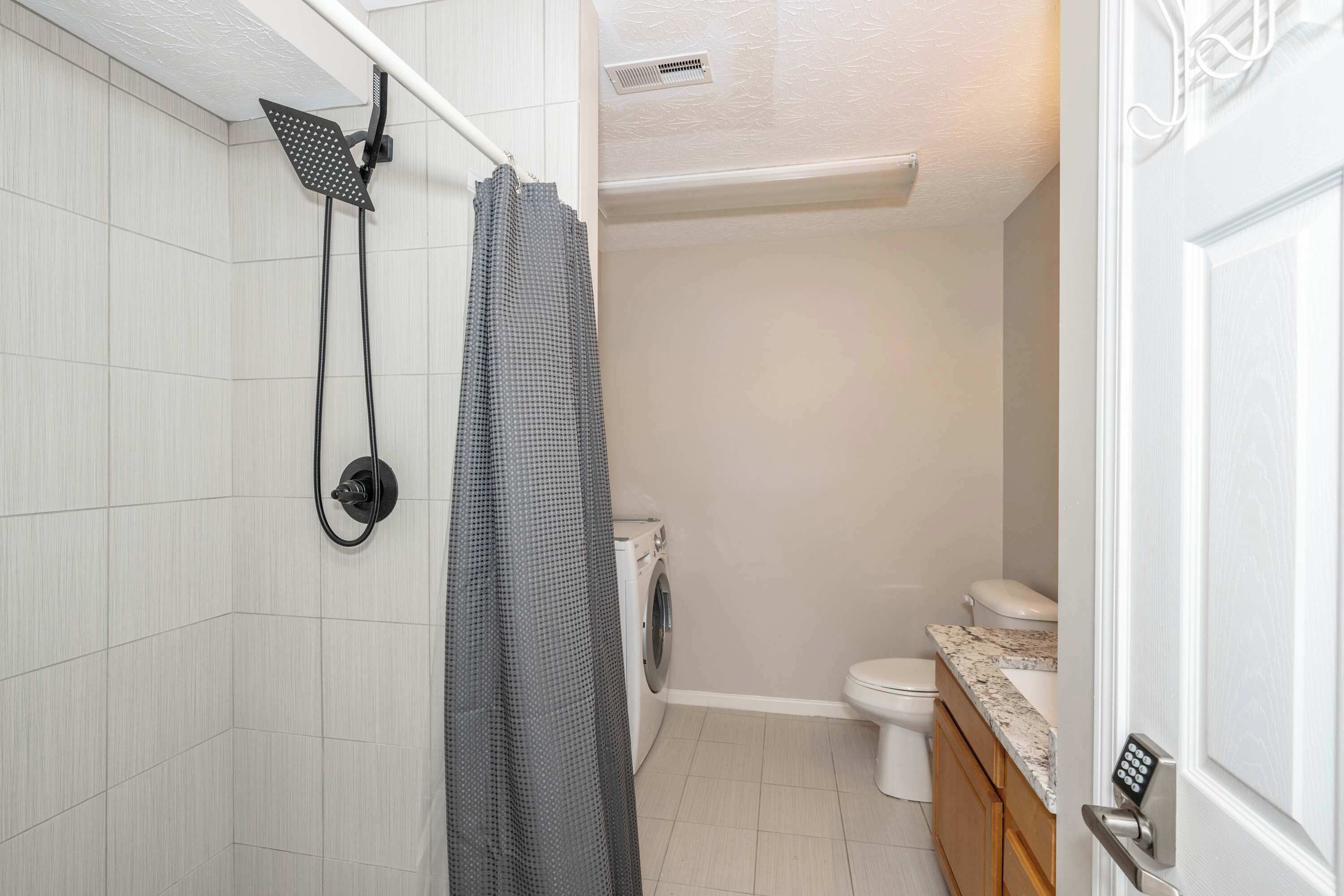 A bathroom with a shower, toilet, and washing machine.