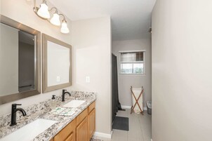 Un baño con dos lavamanos, un espejo grande y una zona de ducha.