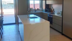 A modern kitchen with a central island, built-in appliances, and a large window providing natural light. - Cozy City Escape in Galway (Galway)