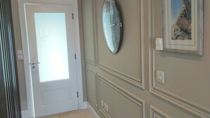 A hallway with a door, a wall-mounted clock, and a framed picture. - Cozy City Escape in Galway (Galway)