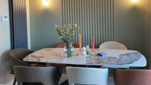 A dining area with a round table, four chairs, a vase of flowers, candles, and wall-mounted lights. - Cozy City Escape in Galway (Galway)
