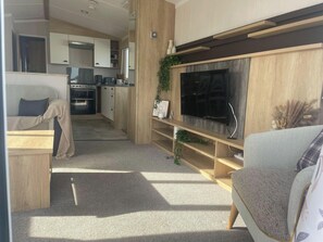 Een moderne woonkamer met een grote flatscreen televisie, houten planken en een gezellige zithoek.