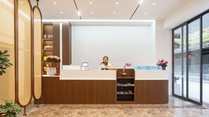 Un mostrador de recepción con encimera blanca, paneles de madera y una puerta de cristal que da al exterior.