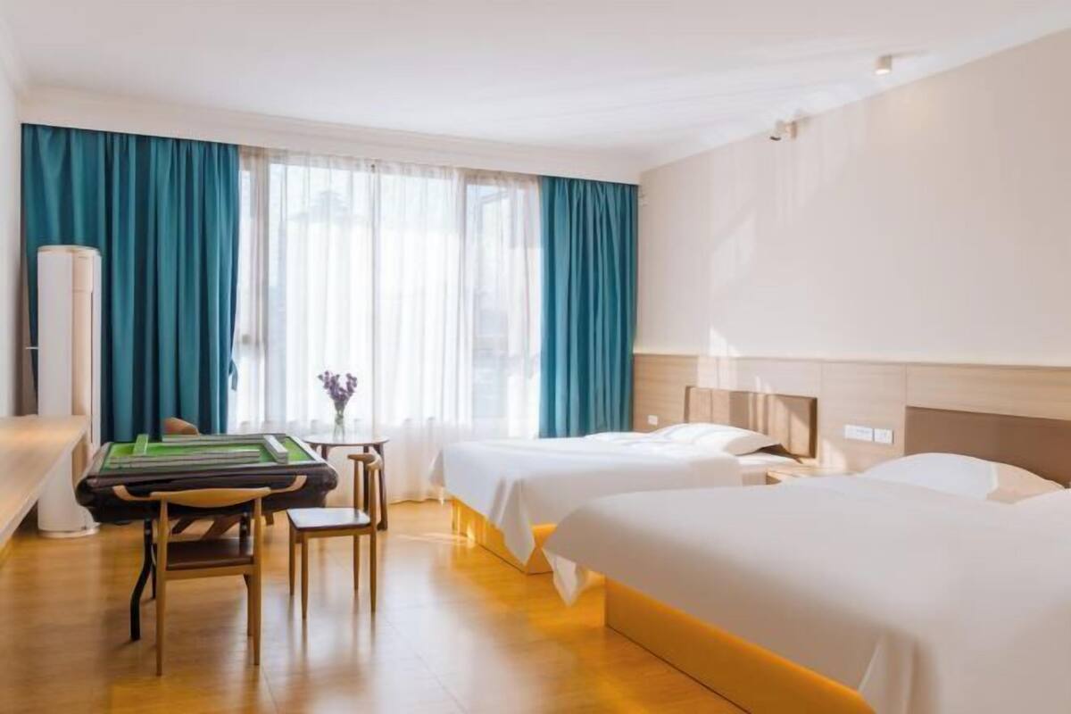 Habitación de hotel con dos camas, mesa de billar y un ventanal grande con cortinas.