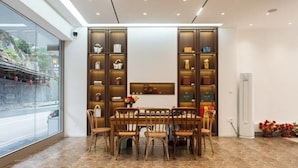 Un comedor con piso de mármol, sillas de madera y una mesa central.