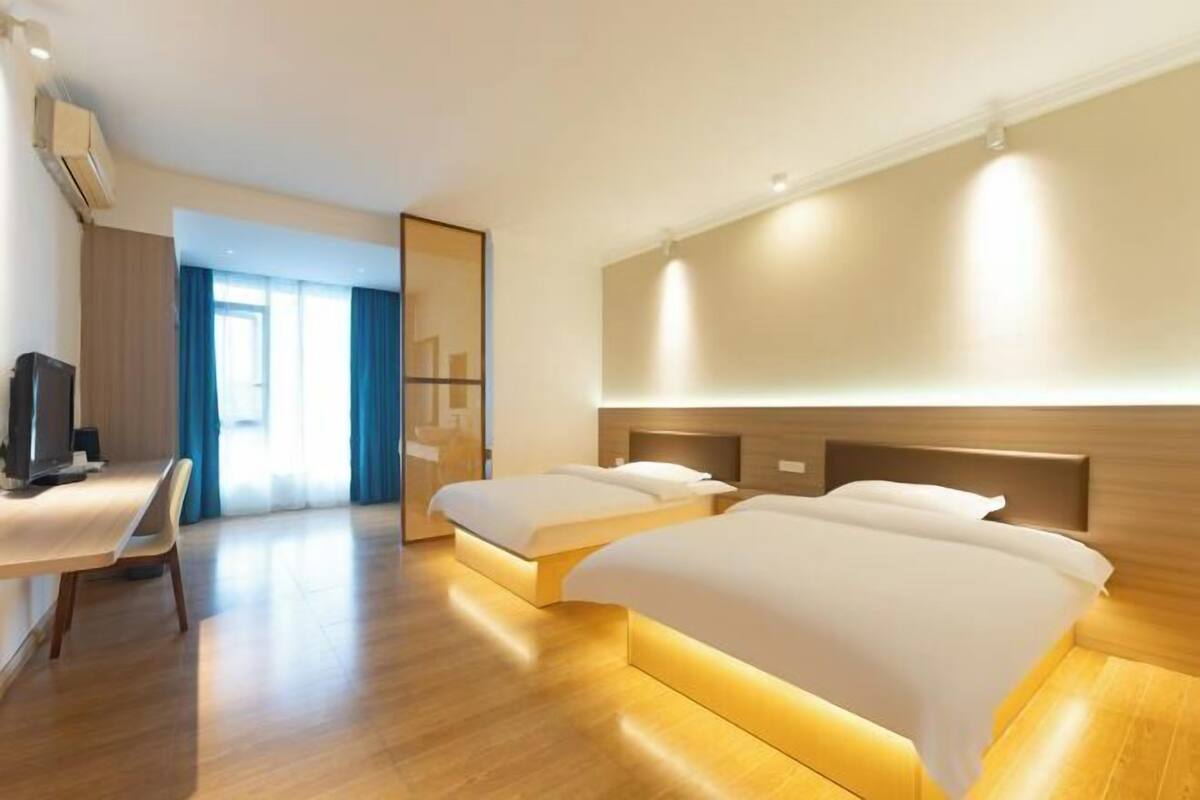 Habitación de hotel con dos camas, un escritorio, un televisor y un espejo grande.