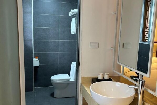 Une salle de bain moderne avec des toilettes blanches, un grand miroir et un lavabo blanc.