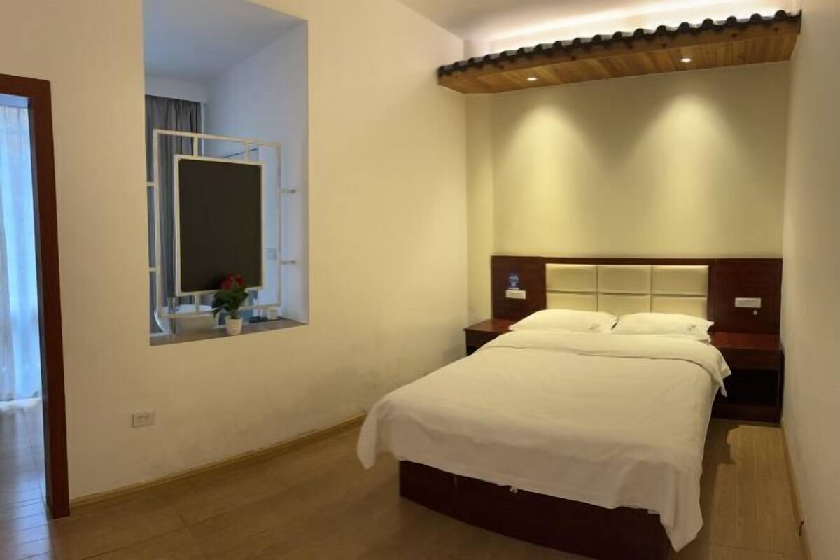 Una habitación de hotel con una cama, una mesita de noche, un espejo y un techo de madera.