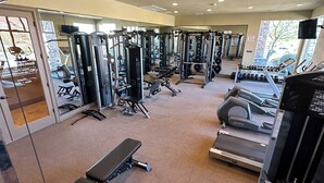 Ein Fitnessstudio mit verschiedenen Trainingsgeräten, darunter Laufbänder, Kraftgeräte und Kurzhanteln.