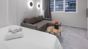 A modern hotel room with a bed, a sofa, and a small round table with a vase of flowers. - Bitola, Nilie Hospitality MGMT (Thessaloniki)