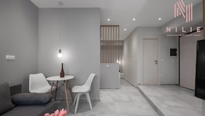 A modern hotel room with a grey sofa, white chairs, a small table, and a decorative vase. - Bitola, Nilie Hospitality MGMT (Thessaloniki)