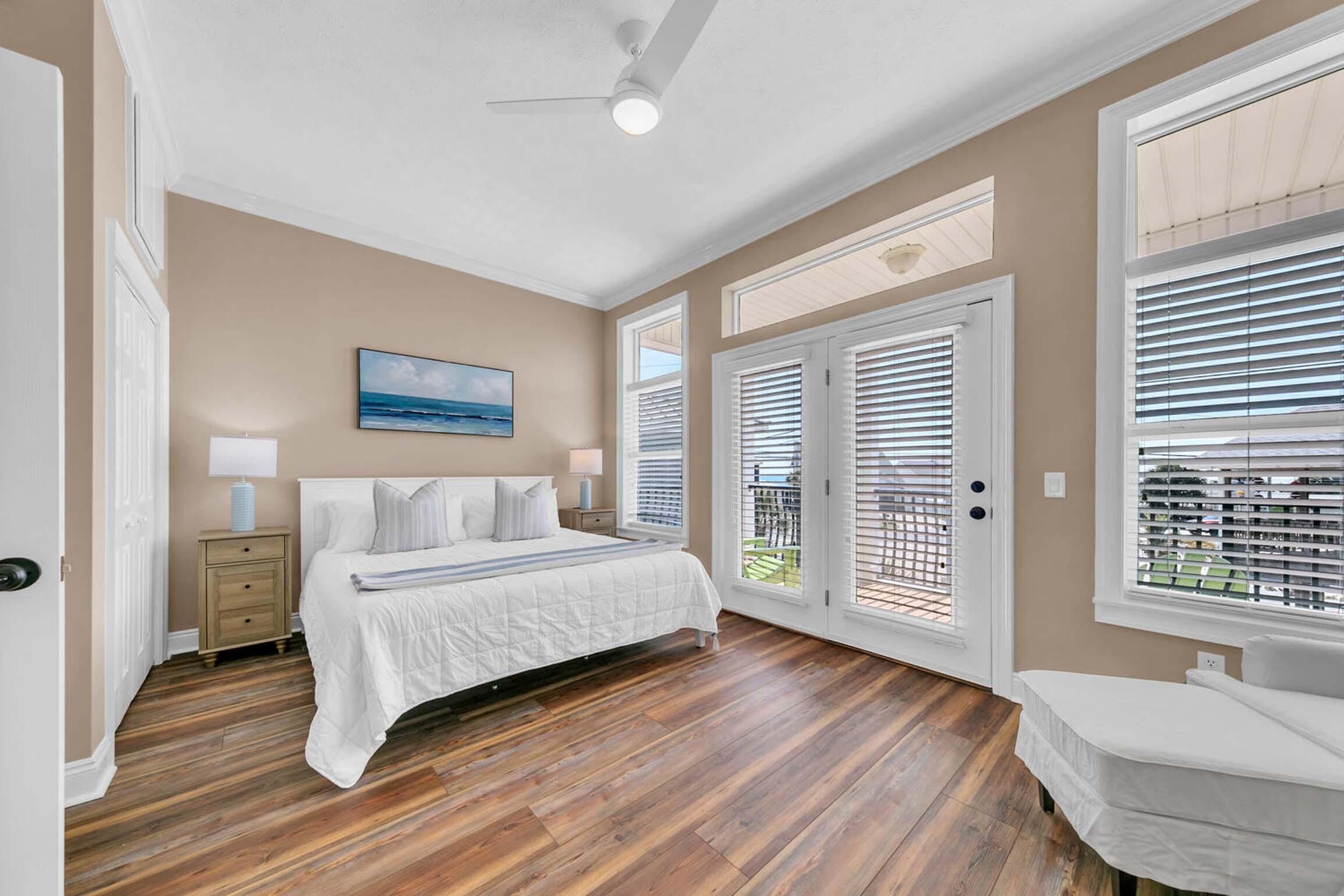 A bedroom with a bed, bedside tables, a ceiling fan, and a view through the door.
