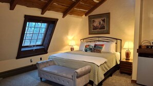 A bedroom with a bed, two bedside tables, a bench, a window, and a painting on the wall. - Inn at Lake Joseph (Forestburgh)