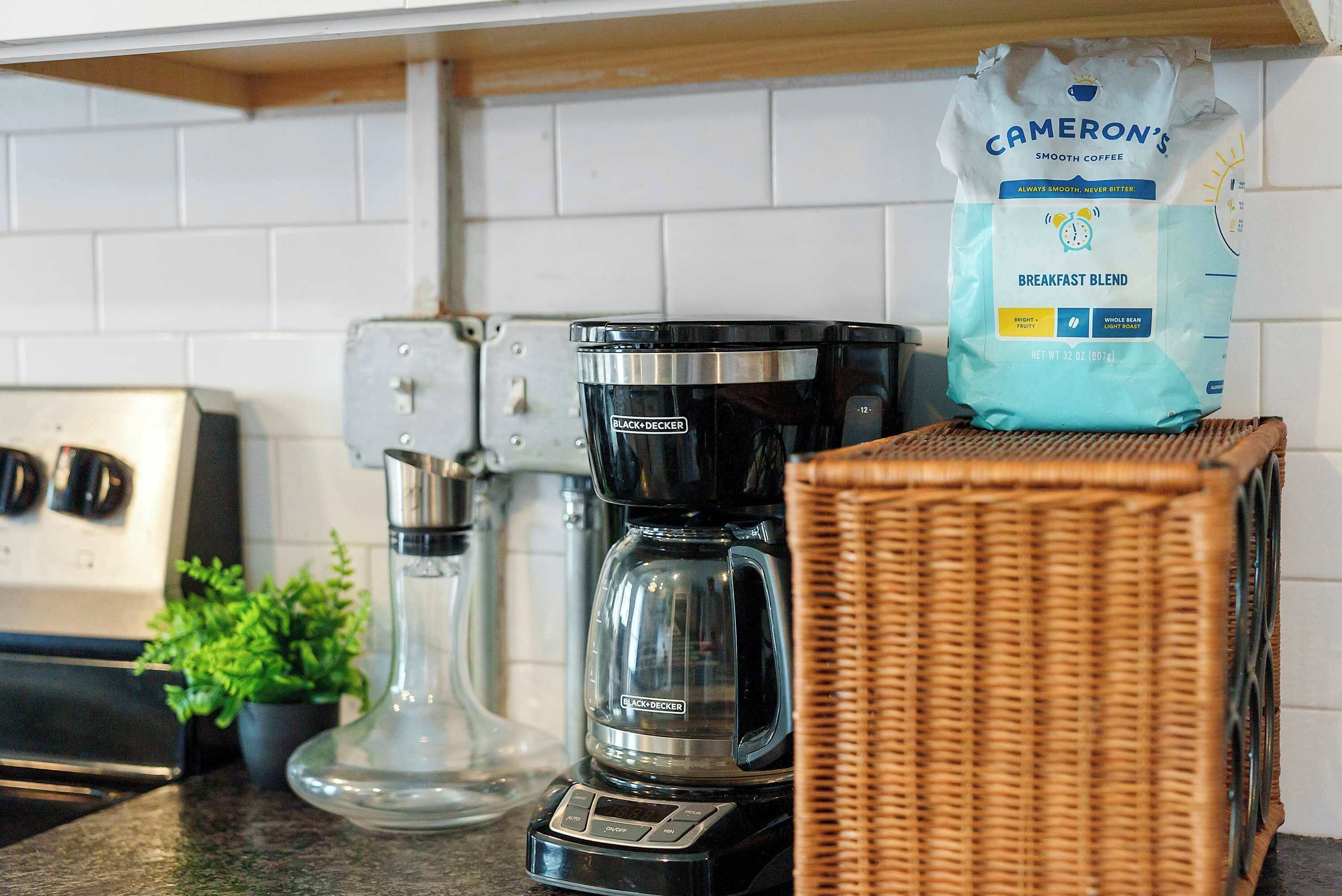 Een keukentafel met een koffiezetapparaat, een zak koffie en een rieten mand.