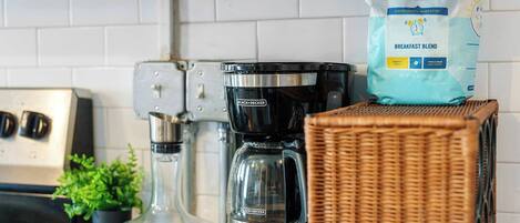 Een keukentafel met een koffiezetapparaat, een zak koffie en een rieten mand.