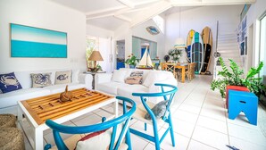 A spacious living area with a white sofa, blue chairs, and a wooden coffee table.