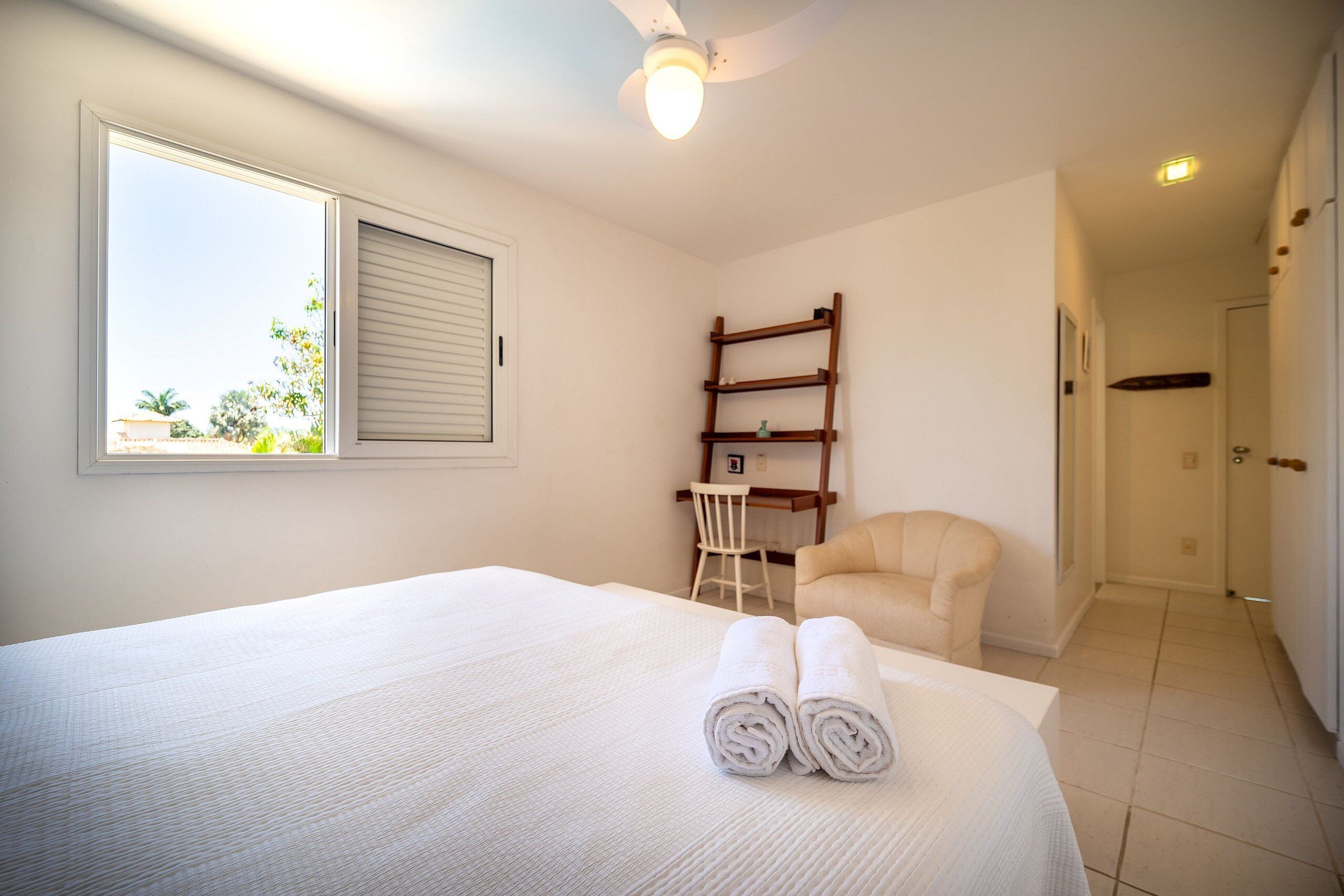 Una habitación de hotel con cama, una silla, escritorio y armario.