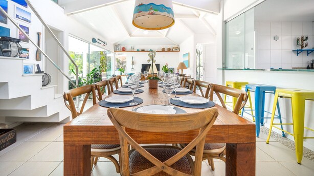 A dining area with a wooden table set for six, surrounded by wooden chairs with woven seats.
