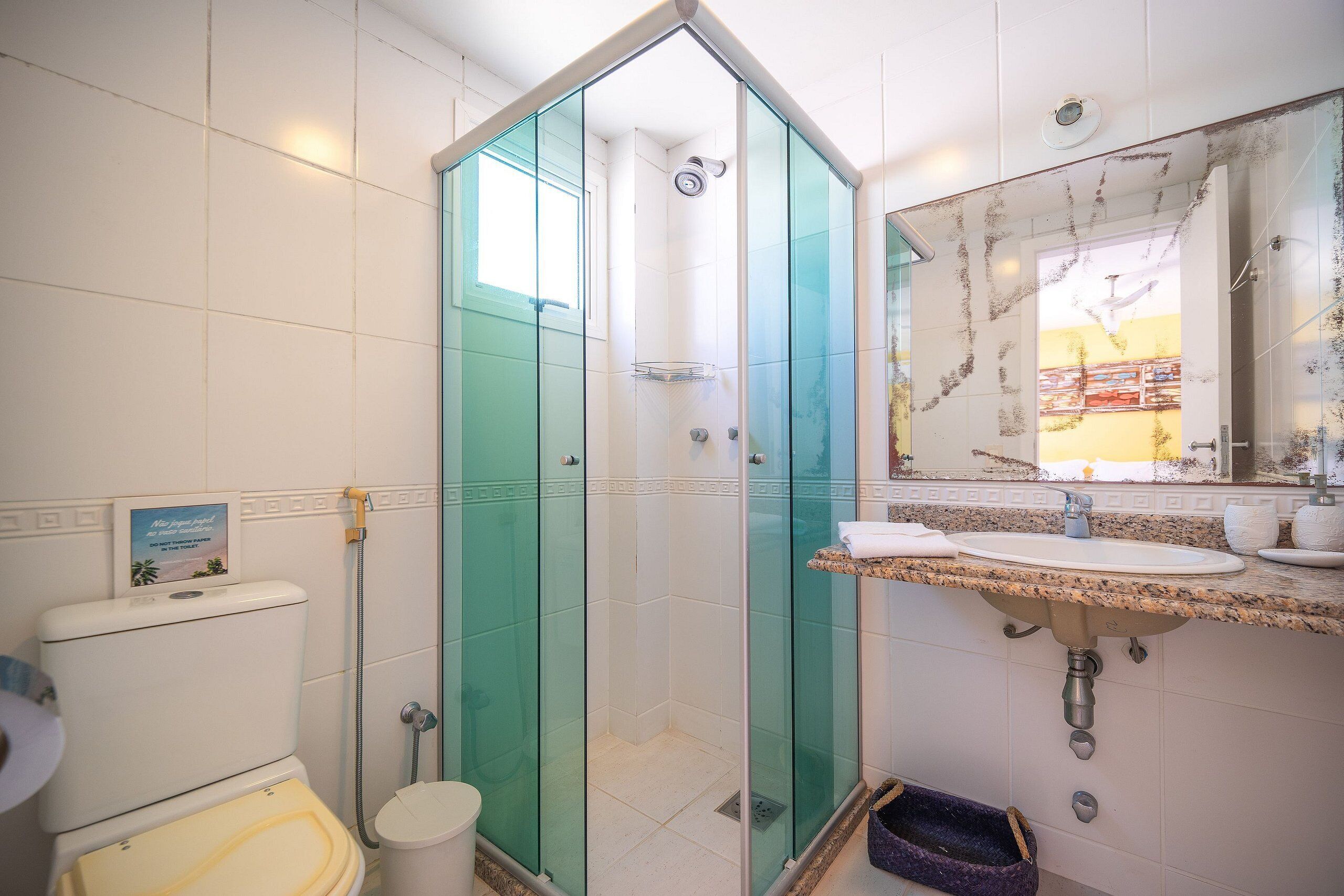 A bathroom with a glass-enclosed shower, a sink with a marble countertop, and a toilet.