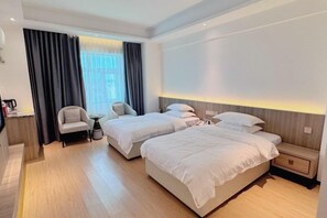 Een hotelkamer met twee bedden, een bureau, een stoel en een raam met gordijnen.