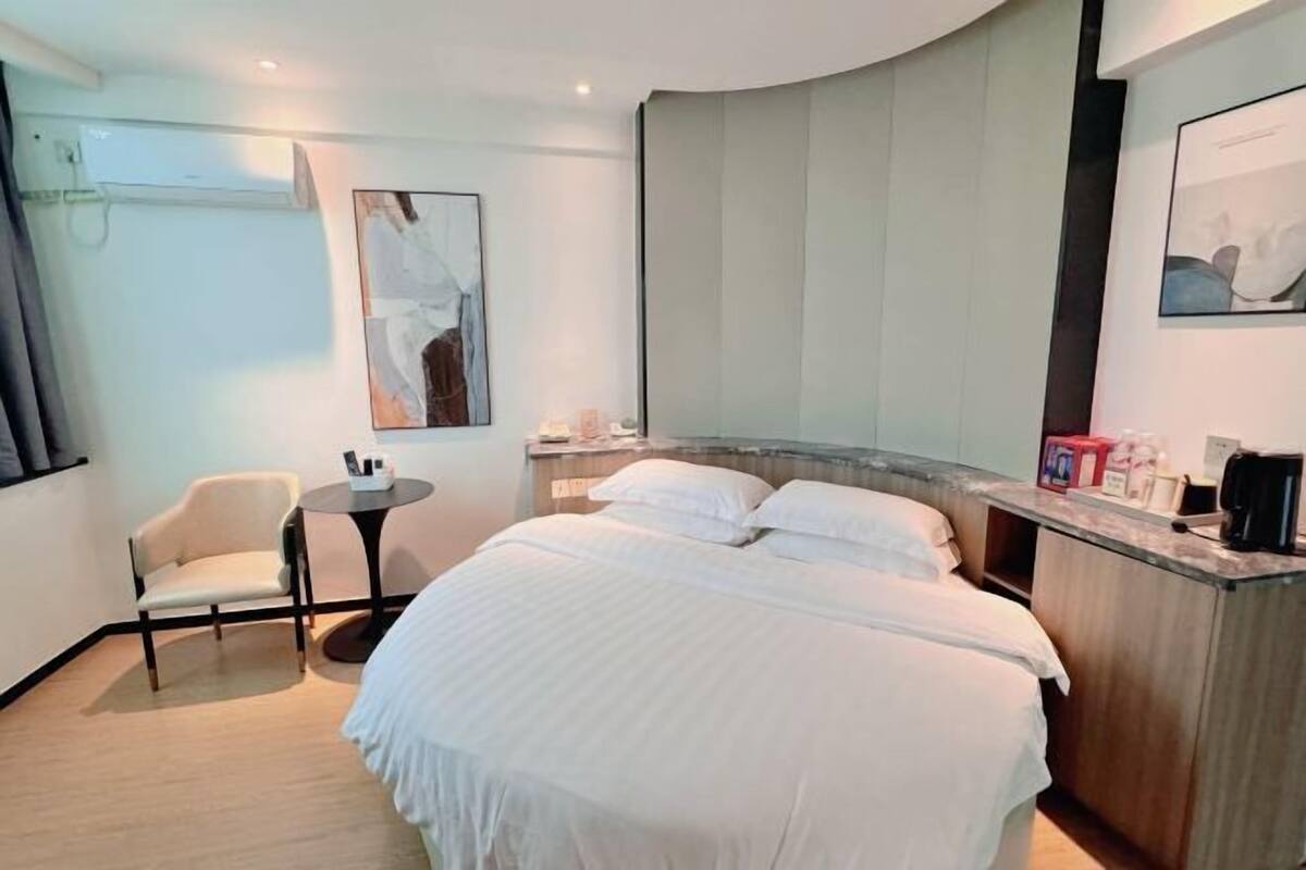 Ein Hotelzimmer mit Bett, Stuhl, kleinem Tisch und Bildern an den Wänden.