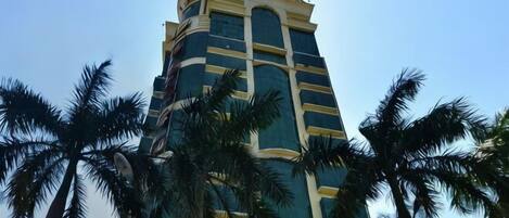 A tall building with a curved facade, surrounded by palm trees.