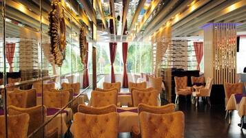 A restaurant with a long dining area, high ceilings, and a view through large windows.