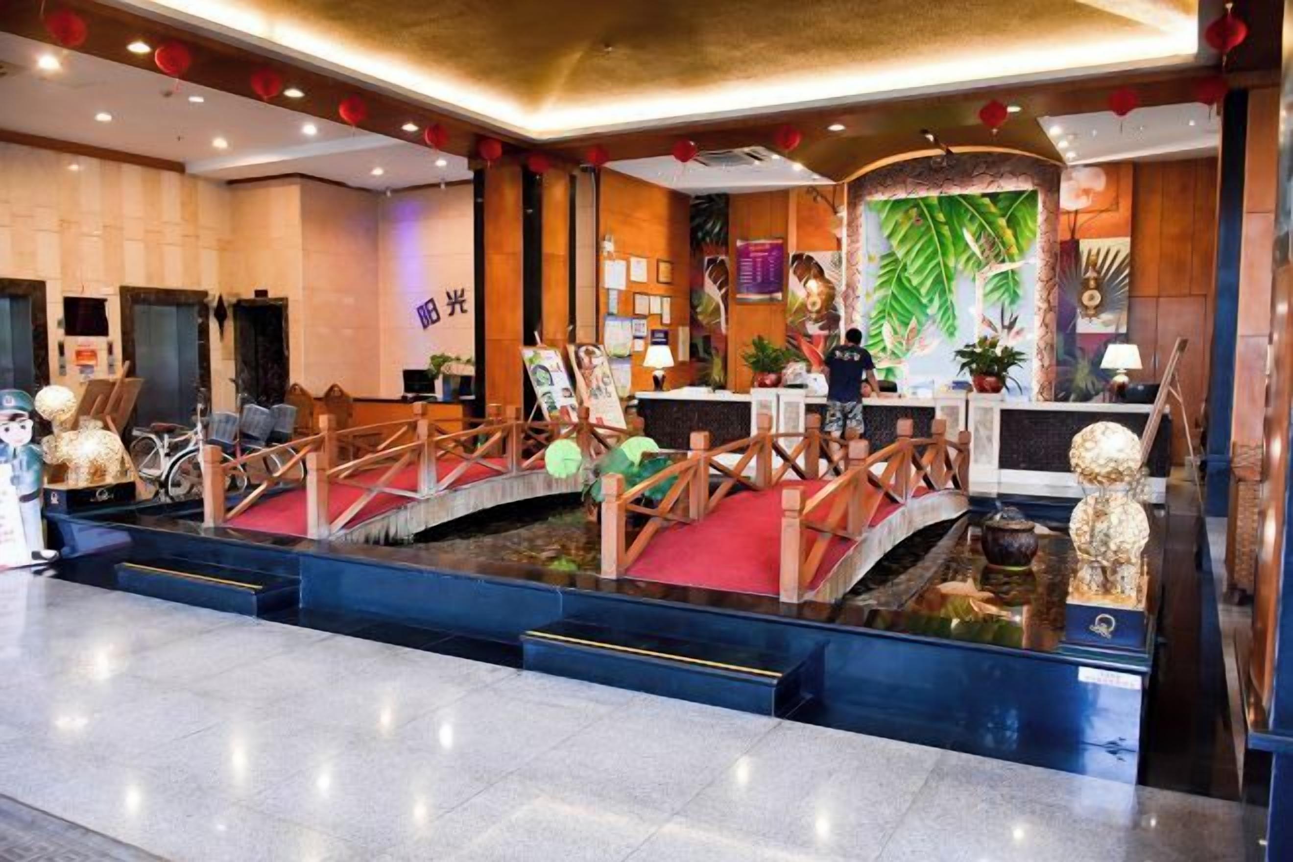 Un hall d’hôtel comprenant un comptoir d’accueil, une fontaine décorative et un pont.