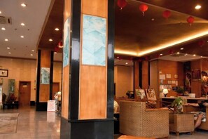 Een hotellobby met een receptiebalie, een zithoek en kunstwerken aan de muren.