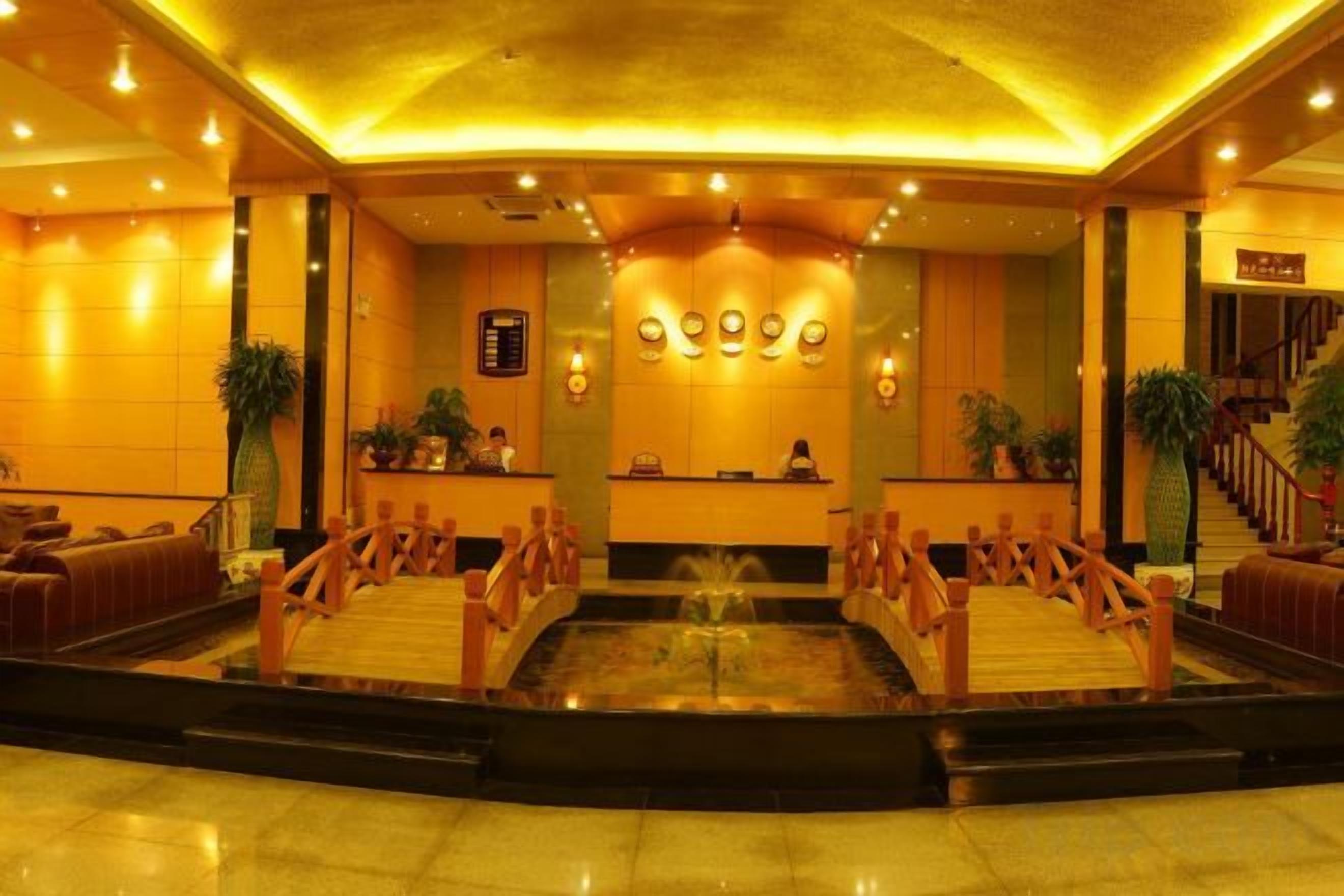 Un vestíbulo de hotel con mostrador de recepción, zona de estar y una fuente.