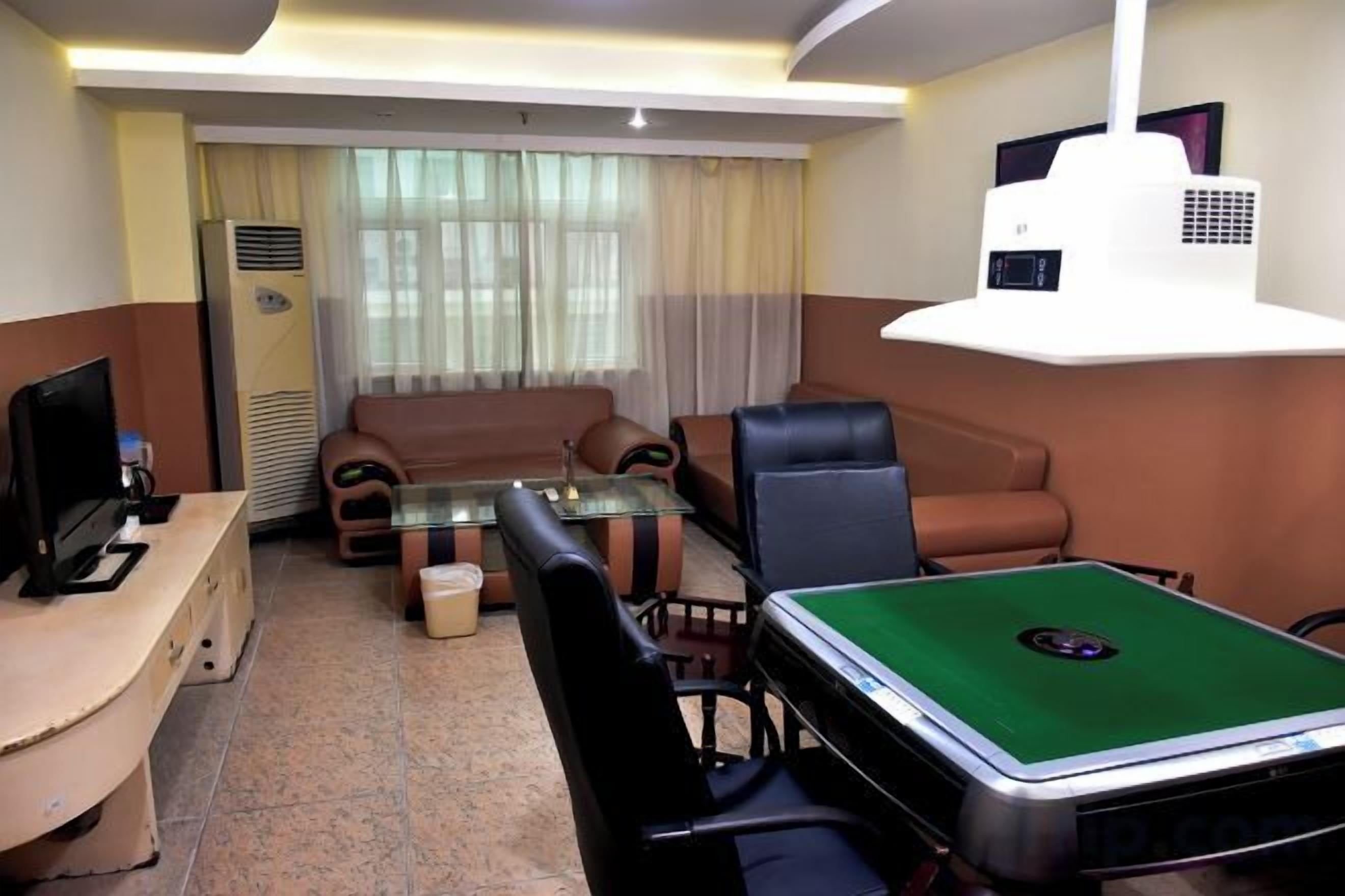 Uma sala de estar com sofá, cadeiras, mesa de centro, mesa de bilhar, TV e projetor.