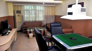 Uma sala de estar com sofá, cadeiras, mesa de centro, mesa de bilhar, TV e projetor.