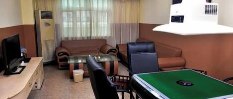 Una sala de estar con sofá, sillas, una mesa de centro, billar, televisor y proyector.