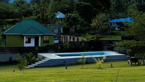 A residential area with houses, a swimming pool, and a mountain in the background. - Rafiki Retreat (Arusha)