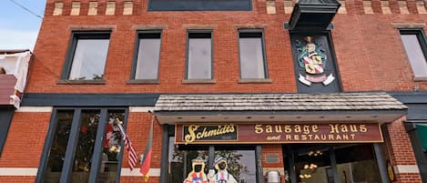 Un bâtiment en briques sur lequel on peut lire l’enseigne « Schmidt’s Sausage Haus and Restaurant », et un emblème décoratif au-dessus de l’entrée.