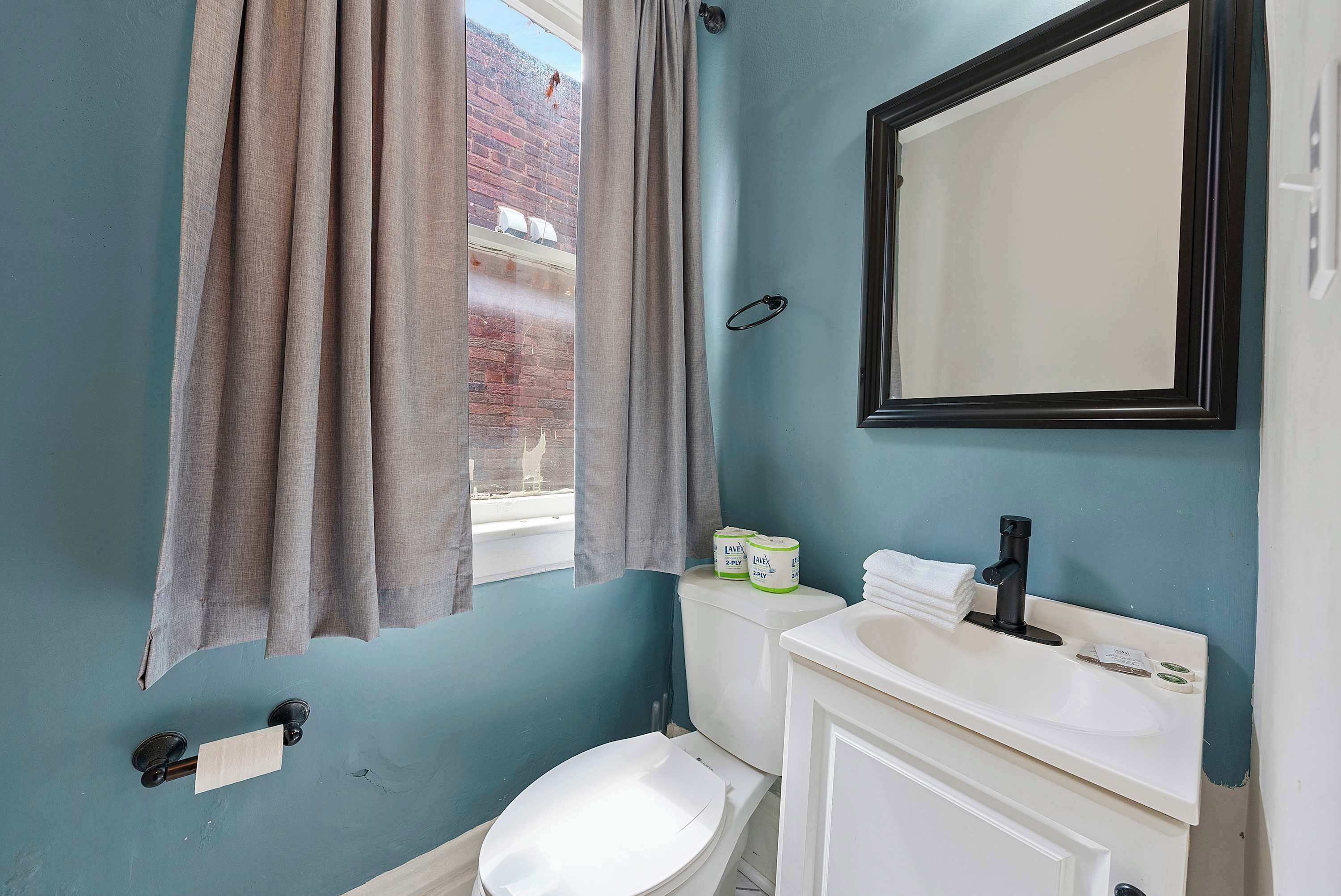 A bathroom with a toilet, sink, and mirror.