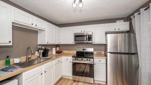 A modern kitchen with white cabinets, stainless steel appliances, and a wooden countertop. - The Ark Encounter Getaway (Williamstown)