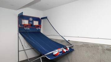 A small indoor basketball court with a blue floor, two basketball hoops, and a net.