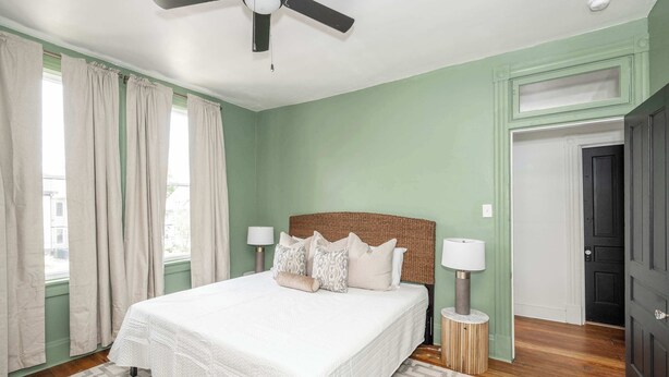 Un dormitorio con cama, dos lámparas de noche, ventilador de techo y una puerta.